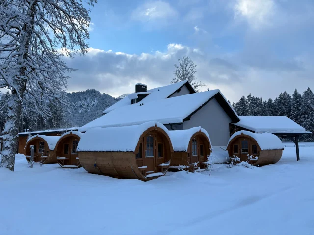 Verschneite Schlaffässer vor dem Haupthaus mit Bergblick